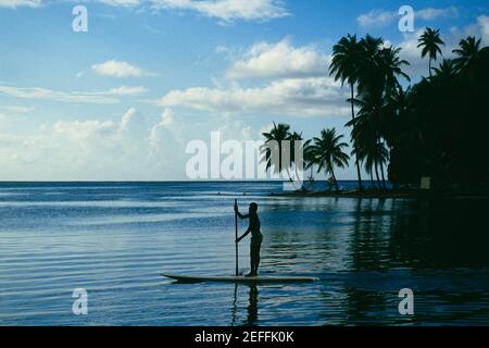 Silhouette eines Mannes rudern ein Boot in einem ruhigen Meer, St. Lucia Stockfoto