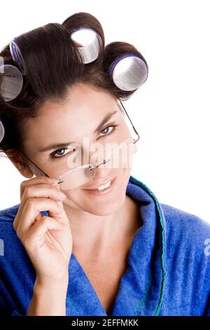Porträt einer jungen Frau mit Lockenwicklern im Haar Ihre Brille einstellen Stockfoto