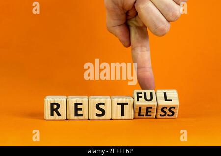 Symbol „Restless“ oder „RESTful“. Geschäftsmann dreht Holzwürfel, ändert das Wort "stlos" in "stful". Schöner orangefarbener Tisch, orangefarbener Hintergrund, Kopie Stockfoto