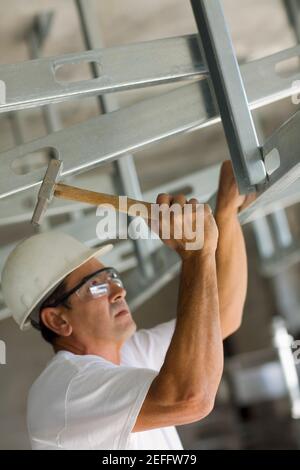 Reifer Mann schlagen mit einem Hammer und Befestigung Stockfoto