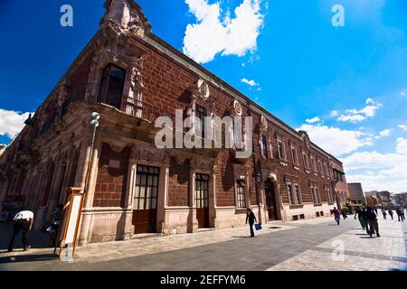 Eine Gruppe von Menschen, die vor einem Regierungsgebäude, Palacio De Gobierno, Aguascalientes, Mexiko, spazieren gehen Stockfoto