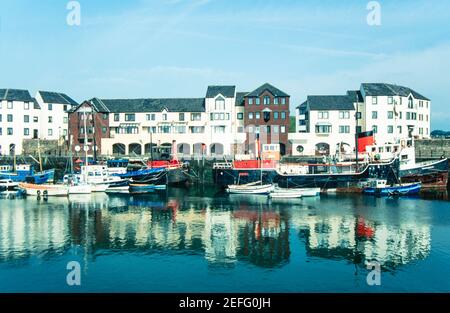 1992 Maryport Cumbria - das Elizabeth Dock bildet das Herz des funktionierenden Hafens von Maryport und ist die Heimat der Fischereiflotte, wenn sie sich im Hafen befindet. Das Elizabeth Dock, benannt nach Elizabeth Senhouse, wurde am 20th. Oktober 1857 eröffnet.die Familie Senhouse war Grundbesitzer in der Gegend und verantwortlich für die Entwicklung der Stadt und Ausgrabungen ihrer römischen Vergangenheit.Humphrey Senhouse nannte die neue Stadt nach seiner Frau Mary. Elizabeth Dock ist Teil des Flusses Ellen Flow.Fischerboote in der Sicherheit von Elizabeth Dock und moderne Apartments in der Cumbrian Stadt Maryport Cumbria England GB UK Europa Stockfoto