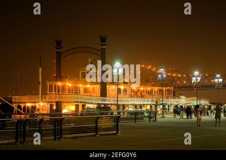 Gruppe von Menschen, die vor einem beleuchteten Raddampfer vor einem Hafen, New Orleans, Louisiana, USA, festmachen Stockfoto