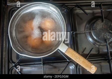 Eier kochen in einer Pfanne mit kochendem Wasser auf einem Gaskochfeld. Stockfoto