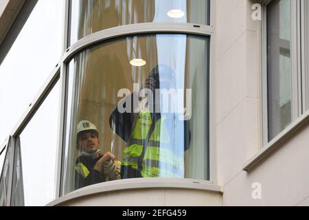 Arbeiter Filmen die Sammelmedien durch ein Fenster mit Blick auf den Eingang des King Edward VII Hospital, London, wo der Herzog von Edinburgh als Vorsichtsmaßnahme auf Anraten seines Arztes aufgenommen wurde, nachdem er sich unwohl gefühlt hatte. Bilddatum: Mittwoch, 17. Februar 2021. Stockfoto