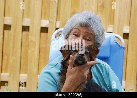 Portrait einer älteren Frau küssen einen Hund Stockfoto