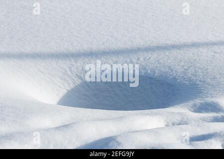 Echtes Loch im klaren Schnee an sonnigen schönen Wintertag Stockfoto