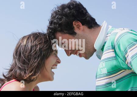 Seitenansicht eines jungen Paares einander betrachtend und lächelnd Stockfoto