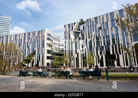 Der Komplex "Kö-Bogen", entworfen vom New Yorker Stararchitekten Daniel Libeskind, wurde 2013 fertiggestellt. Menschen sitzen auf Bänken und genießen das schöne Wetter. Stockfoto