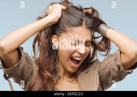 Nahaufnahme einer jungen Frau, die mit ihren Händen in ihre Haare schreien Stockfoto