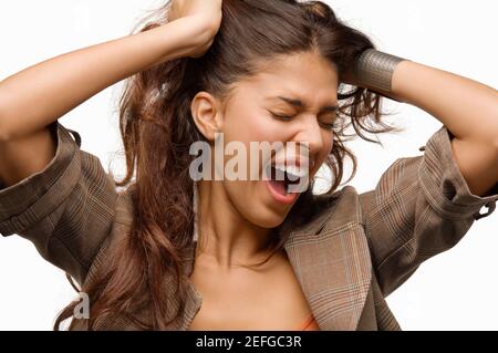 Nahaufnahme einer jungen Frau, die mit ihren Händen in ihre Haare schreien Stockfoto