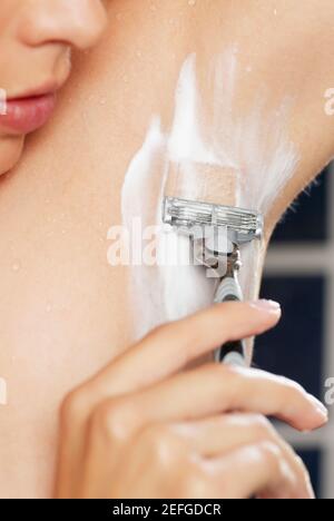 Nahaufnahme einer jungen Frau, die ihre Achselhöhle rasiert Stockfoto