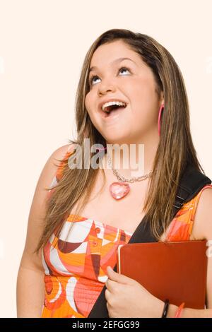Nahaufnahme einer jungen Frau hält ein Tagebuch und lächelnd Stockfoto