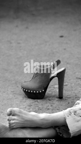 Eine Frau, die sich in einem Park entspannt, entfernt ihre hohe Fersenplateaus Clog Sandale in Santa Fe, New Mexico Stockfoto