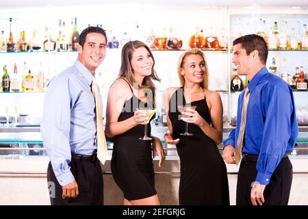 Zwei Männer mittleren Erwachsenen und zwei Frauen mittleren Erwachsenen stehen In einer Bar Stockfoto