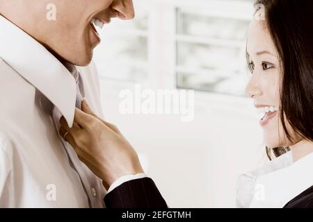 Seitenprofil einer Geschäftsfrau, die eine businessmanÅ½s Krawatte anpasst Stockfoto
