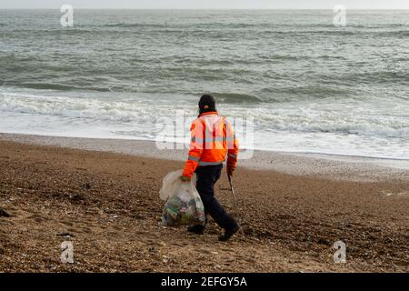 Mann, der nach einem Sturm Müll am Strand sammelt. Hayling Island, Hampshire. Stockfoto