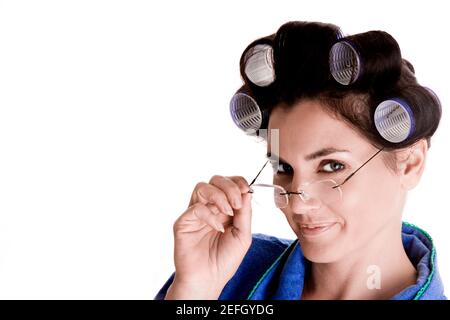 Porträt einer jungen Frau mit Lockenwicklern im Haar Ihre Brille einstellen Stockfoto