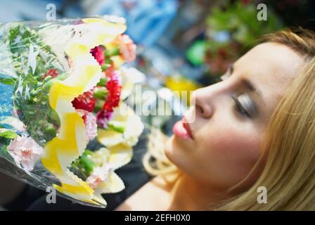 Seitenprofil einer jungen Frau, die einen Strauß riecht Blumen Stockfoto