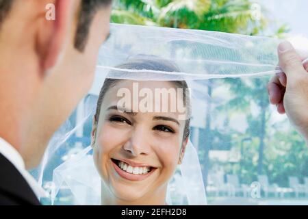 Nahaufnahme eines Bräutigams, der seinen brideÅ½s-Schleier hebt Stockfoto
