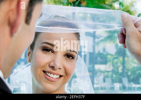 Rückansicht eines Bräutigams, der seinen brideÅ½s Schleier hebt Stockfoto