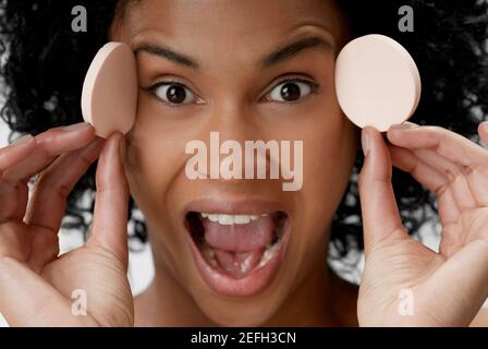 Porträt einer jungen Frau, die Puderpuffs hält Stockfoto