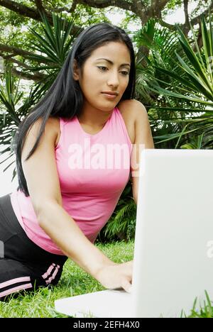 Nahaufnahme einer jungen Frau, die einen Laptop benutzt und sitzt Auf dem Gras Stockfoto