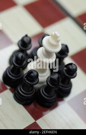 Königsschach, umgeben von Bauern auf einem Schachbrett Stockfoto