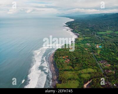 Luftaufnahme der Küste mit schwarzen Sandstränden und Wellen in Balian, Bali Stockfoto