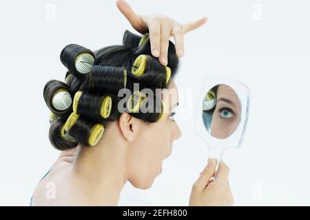 Nahaufnahme einer reifen Frau, die ihre Lockenwickler anpasst Stockfoto