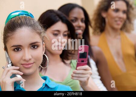 Porträt eines Teenagers, das auf einem Mobiltelefon spricht Mit drei Mädchen im Teenageralter hinter ihr Stockfoto