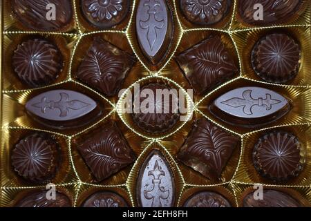 Schokoladen-Bonbons in verschiedenen Formen in einer Goldschachtel, Draufsicht. Verschiedene Schokoladenpralinen. Stockfoto