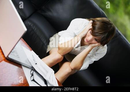 Geschäftsfrau sitzt auf einer Couch und sieht besorgt aus Stockfoto