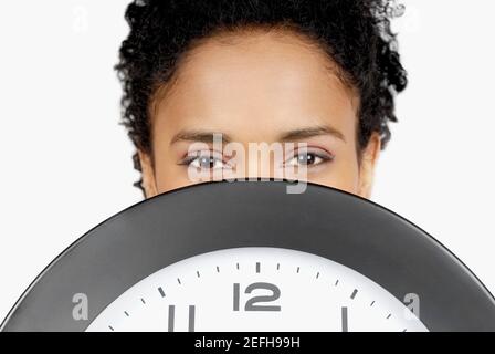 Porträt einer Geschäftsfrau versteckt ihr Gesicht hinter einer Uhr Stockfoto