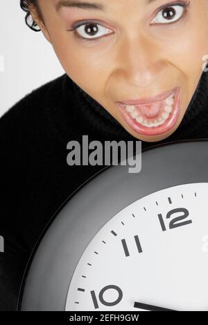 Porträt einer Geschäftsfrau, die eine Uhr mit dem Mund hält Öffnen Stockfoto
