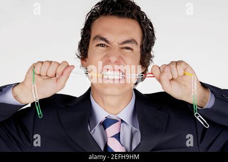 Porträt eines Geschäftsmannes, der eine Kette von Büroklammern beißt Stockfoto
