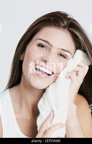 Porträt einer jungen Frau, die ihr Gesicht mit einem Handtuch und Lächeln Stockfoto
