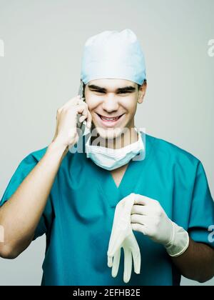 Porträt eines männlichen Chirurgen lächelnd und mit einem Handy Telefon Stockfoto
