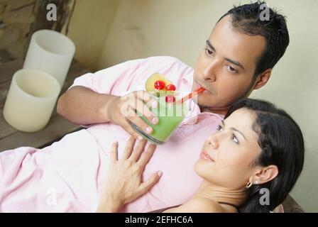 Aus der Sicht eines jungen Mannes, der Saft trinkt Eine junge Frau, die neben ihm sitzt Stockfoto