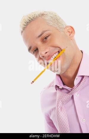 Porträt eines Geschäftsmannes, der lächelt und einen Bleistift zwischen sich hält Seine Zähne Stockfoto