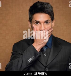 Porträt eines Geschäftsmannes, der seinen Mund mit der Hand bedeckt Stockfoto