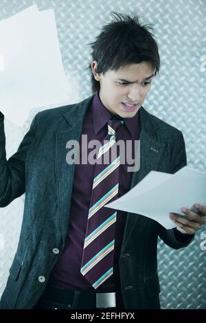 Geschäftsmann runzelte die Stirn und schaute sich Papiere an Stockfoto