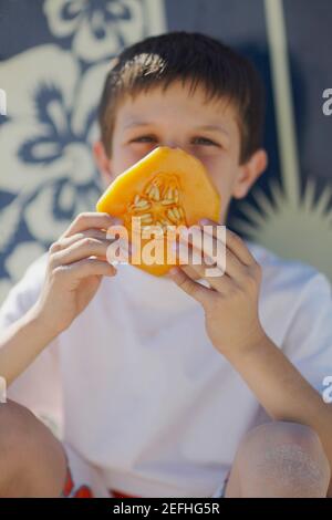 Nahaufnahme eines Jungen im Teenageralter, der eine Scheibe Melone hält Stockfoto