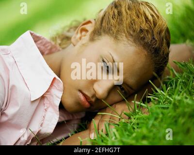 Nahaufnahme einer jungen Frau, die auf dem Gras und liegt Sieht ernst aus Stockfoto