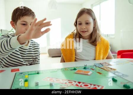 KIEL, DEUTSCHLAND - 14. Februar 2021: Fröhliche Kinder, die gemeinsam mit ihren Eltern Spaß am Brettspiel haben Stockfoto