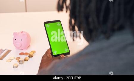 afroamerikanischer schwarzer Mann mit mobilen App für Investitionen. Grüner Bildschirm auf dem Smartphone. Hochwertige Fotos Stockfoto