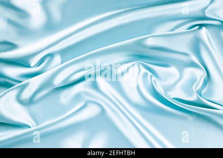 Schöne hellblaue Hintergrund mit Drapierung und welligen Falten aus Seide Satin Material Textur. Draufsicht Stockfoto