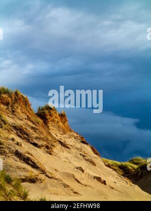 Sanddünen am Strand von Morfa Dyffryn zwischen Barmouth und Harlech in Gwynedd an der Nordwestküste von Wales mit stürmischem Himmel darüber. Stockfoto