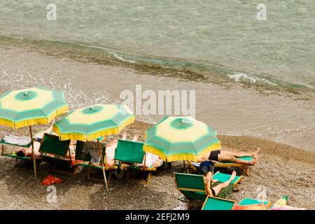 Blick von Touristen, die sich auf Liegestühlen entspannen, Spiaggia Grande, Positano, Amalfiküste, Salerno, Kampanien, Italien Stockfoto