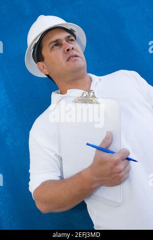 Low-Angle-Ansicht eines männlichen Bauarbeiters mit einem Zwischenablage und einen Stift Stockfoto